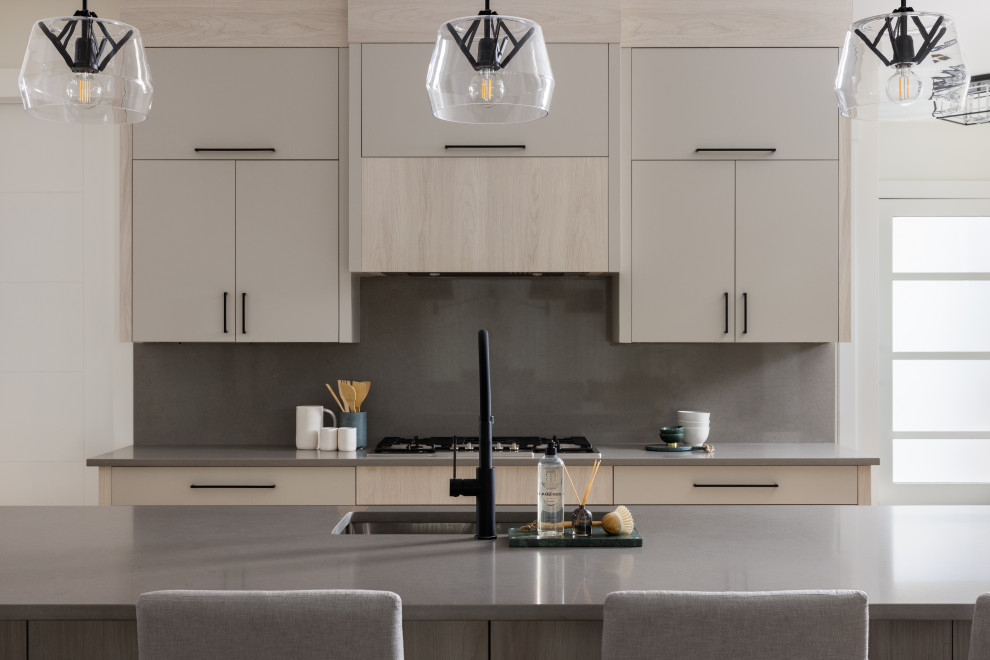 Photo of a mid-sized modern l-shaped eat-in kitchen in Calgary with a double-bowl sink, flat-panel cabinets, light wood cabinets, quartz benchtops, grey splashback, engineered quartz splashback, stainless steel appliances, light hardwood floors, with island, beige floor, grey benchtop and coffered.