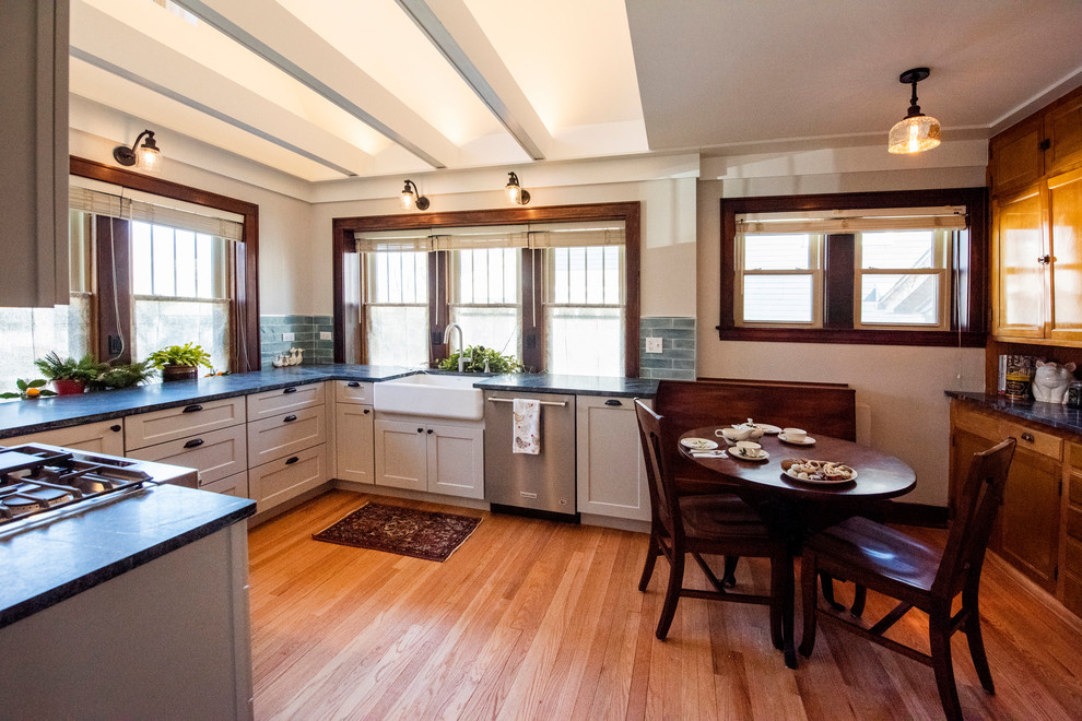 Photo of a small arts and crafts u-shaped eat-in kitchen in Chicago with a farmhouse sink, shaker cabinets, grey cabinets, granite benchtops, blue splashback, glass tile splashback, stainless steel appliances, medium hardwood floors, no island, brown floor and green benchtop.