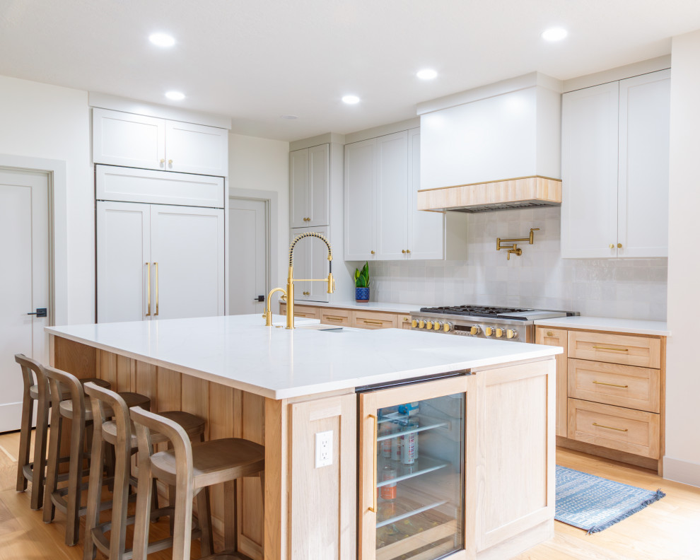 Open concept kitchen - mid-sized transitional light wood floor open concept kitchen idea in Houston with light wood cabinets, white backsplash, porcelain backsplash, paneled appliances, an island and white countertops