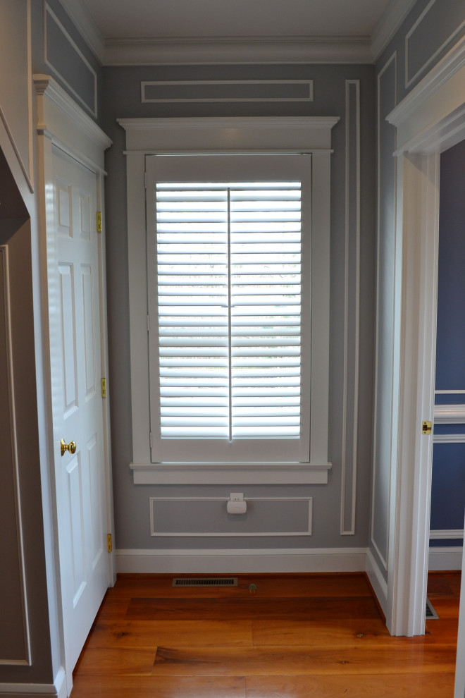 Photo of a mid-sized traditional hallway in Other with blue walls and light hardwood floors.