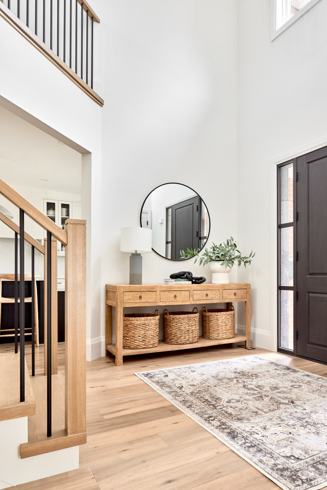 Inspiration for a mid-sized transitional light wood floor, vaulted ceiling and brown floor foyer remodel with white walls and a dark wood front door