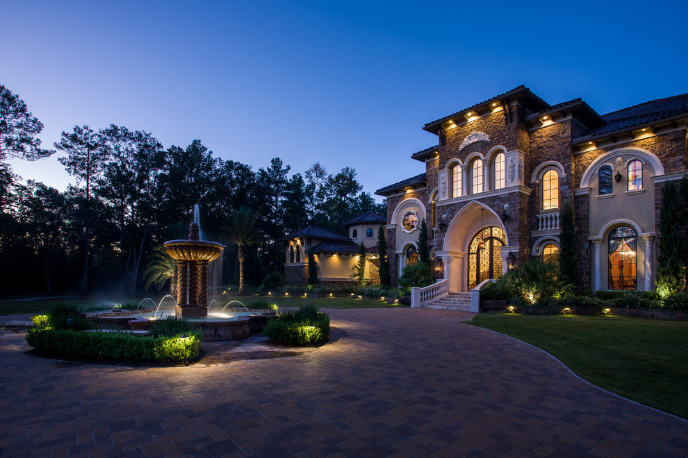 Expansive mediterranean two-storey beige exterior in Houston with stone veneer and a hip roof.