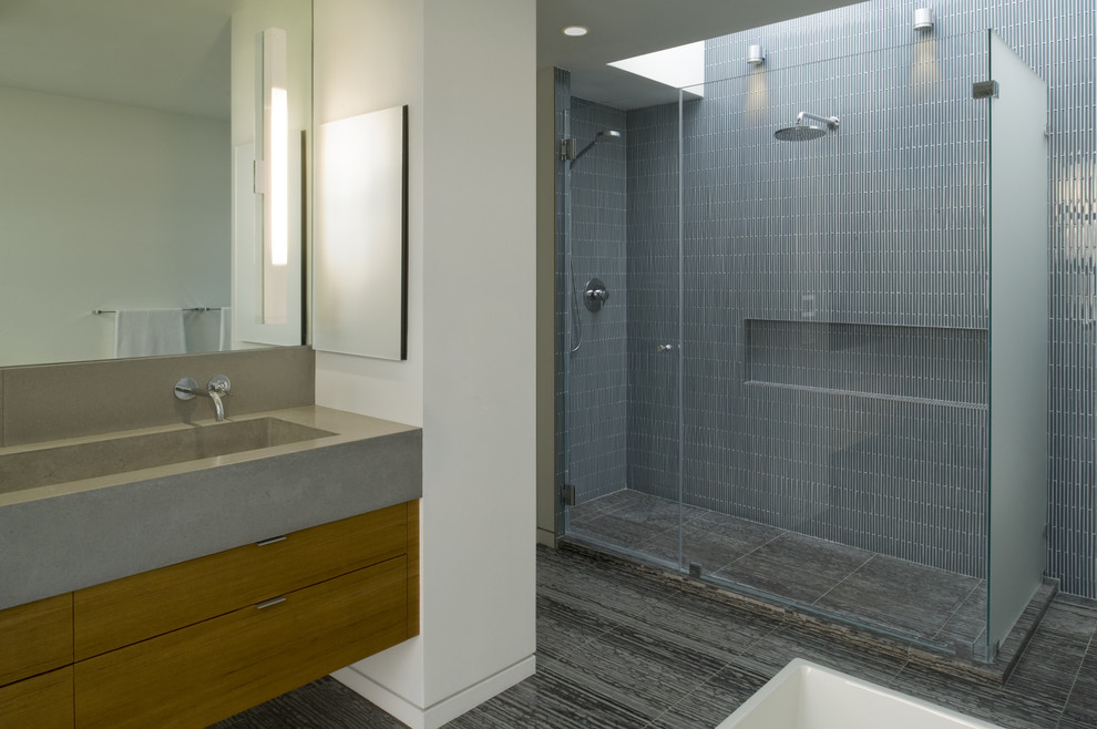 Photo of a modern bathroom in San Francisco with a trough sink, flat-panel cabinets, medium wood cabinets, concrete benchtops, an alcove shower, gray tile and matchstick tile.