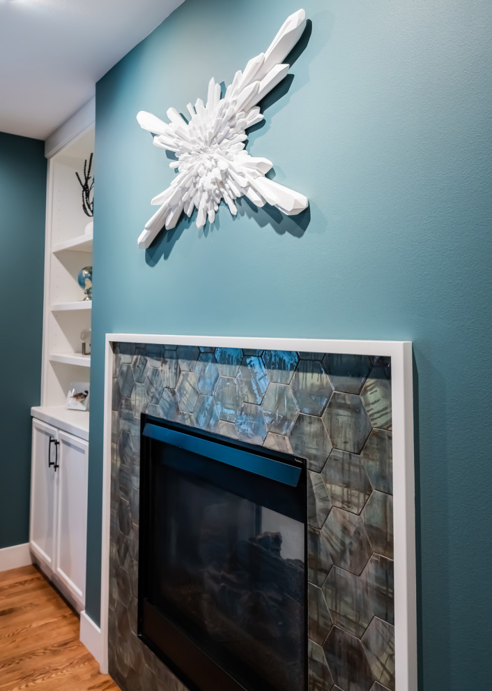 Inspiration pour un bureau minimaliste de taille moyenne avec un mur bleu, un sol en bois brun, une cheminée standard, un manteau de cheminée en carrelage et un sol marron.