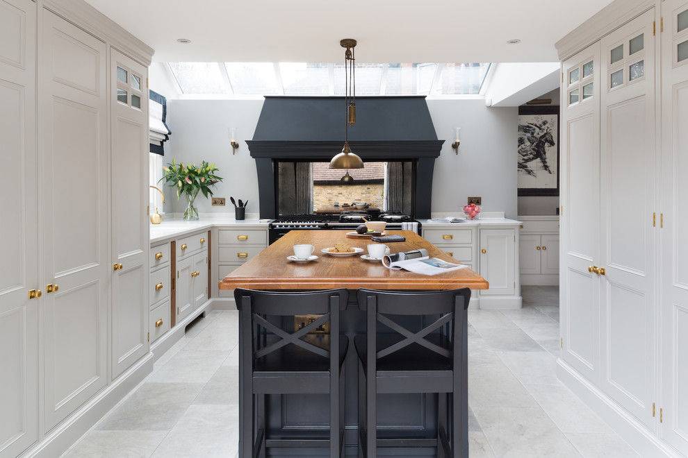 Design ideas for a mid-sized transitional u-shaped kitchen in London with recessed-panel cabinets, grey cabinets, metallic splashback, mirror splashback, with island and grey floor.