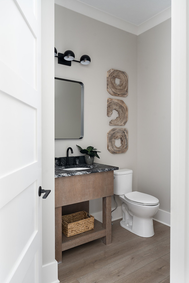 Inspiration for a medium sized modern cloakroom in Indianapolis with flat-panel cabinets, medium wood cabinets, a one-piece toilet, a submerged sink, granite worktops, black worktops and a freestanding vanity unit.