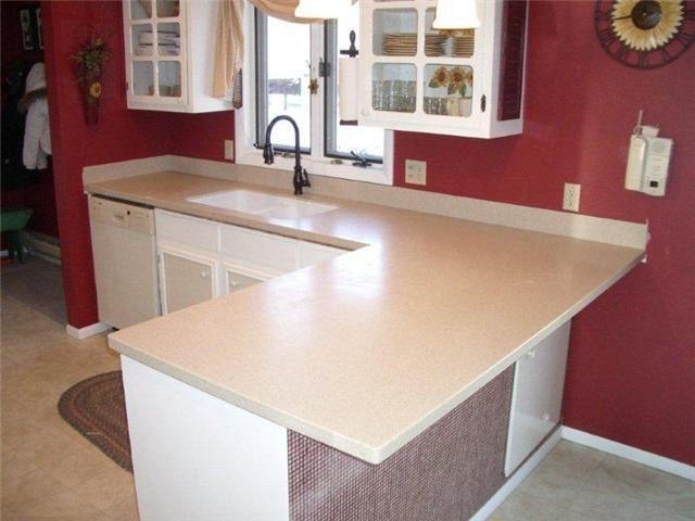 Small traditional l-shaped eat-in kitchen in Other with a double-bowl sink, recessed-panel cabinets, white cabinets, solid surface benchtops, red splashback, ceramic floors and a peninsula.