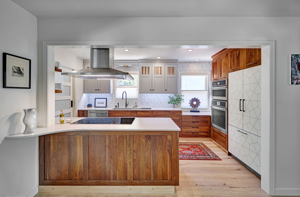 Mid-sized eclectic galley eat-in kitchen in Sacramento with an undermount sink, shaker cabinets, medium wood cabinets, quartz benchtops, white splashback, porcelain splashback, stainless steel appliances, light hardwood floors, a peninsula, multi-coloured floor and white benchtop.