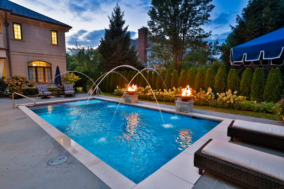 Mid-sized traditional backyard rectangular lap pool in Chicago with with privacy feature and natural stone pavers.
