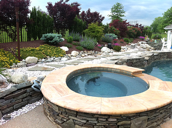 Large transitional backyard stamped concrete and custom-shaped hot tub photo in Philadelphia