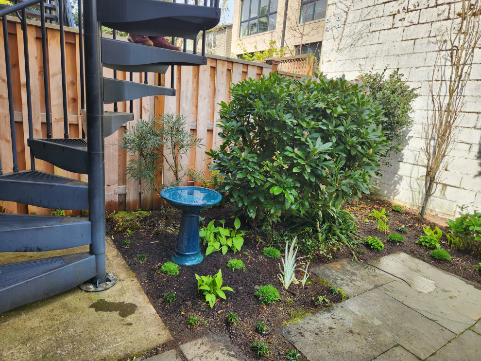 This is an example of a small contemporary courtyard partial sun garden for spring in Portland with with privacy feature, natural stone pavers and a wood fence.