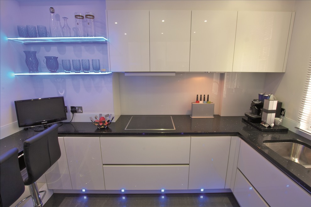 Photo of a small modern u-shaped kitchen in London with white cabinets and glass-front cabinets.