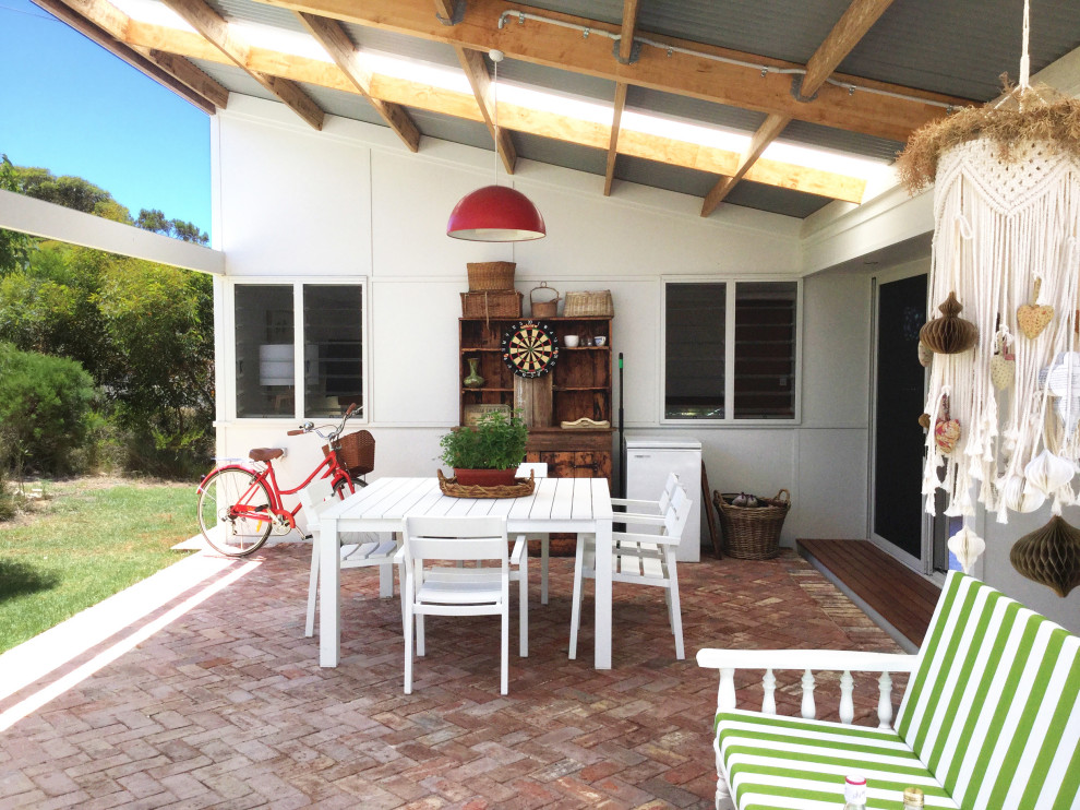 This is an example of a mid-sized beach style courtyard patio in Perth with an outdoor kitchen, brick pavers and a pergola.
