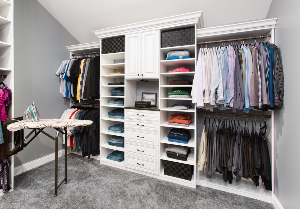 This is an example of a large traditional walk-in wardrobe in Chicago with raised-panel cabinets, white cabinets and carpet.