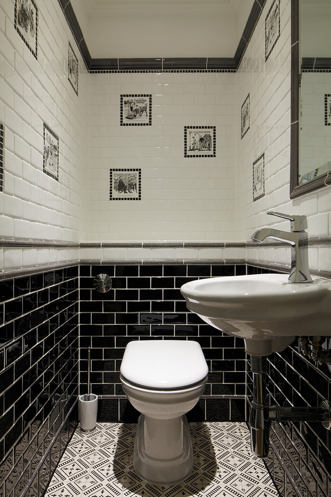 This is an example of a traditional powder room in London with a wall-mount sink, subway tile, a one-piece toilet and black and white tile.
