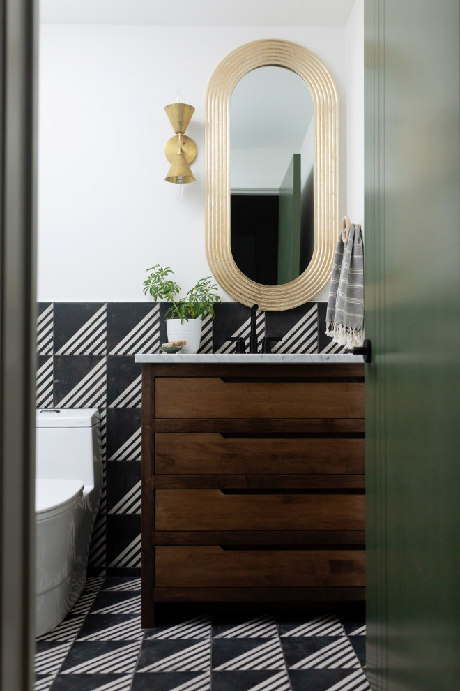 Exemple d'un WC et toilettes tendance en bois brun avec un placard à porte plane, WC à poser, un carrelage noir et blanc, un mur rouge, un lavabo encastré, un plan de toilette en marbre, un sol multicolore, un plan de toilette gris et meuble-lavabo encastré.