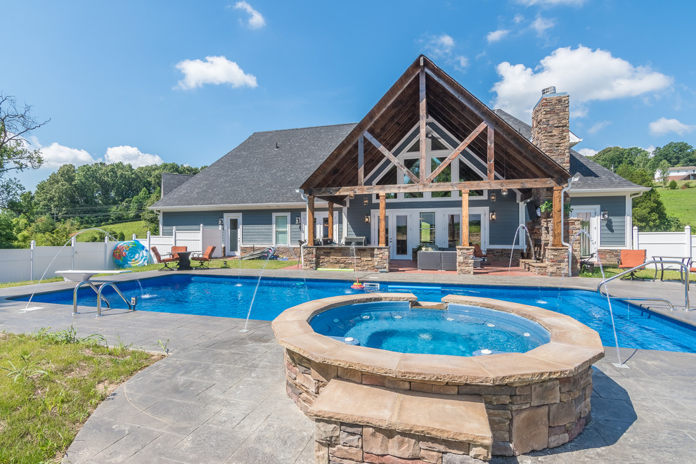 Example of a large mountain style backyard stamped concrete and rectangular lap hot tub design