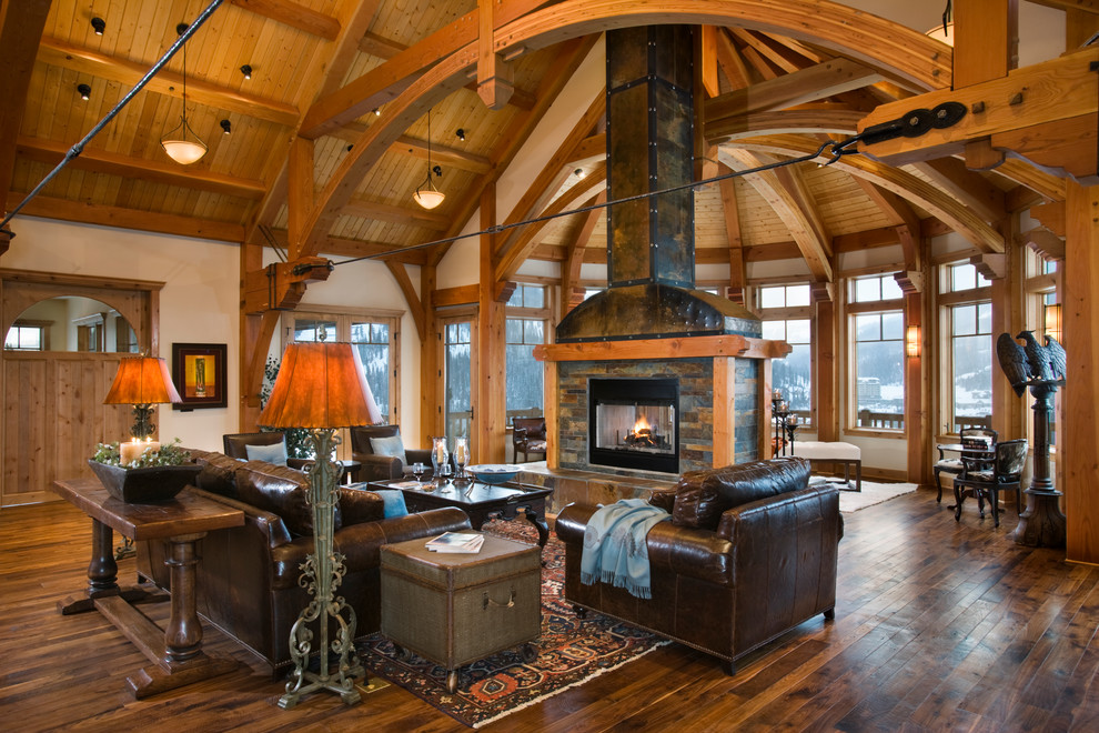 This is an example of a mid-sized arts and crafts open concept living room in Other with beige walls, light hardwood floors, a two-sided fireplace and a stone fireplace surround.