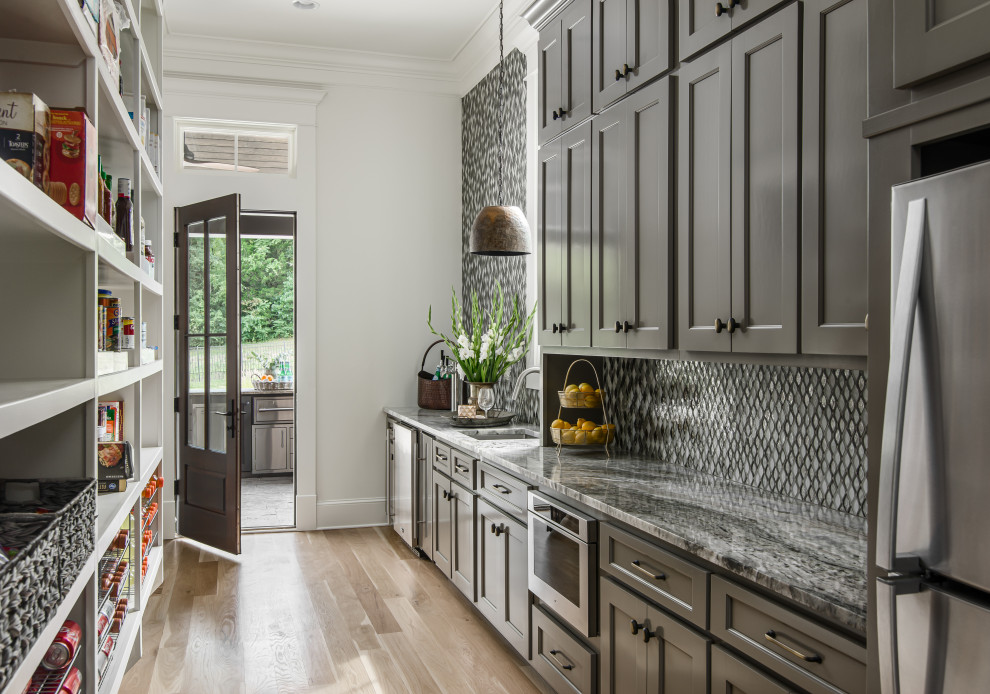 Design ideas for a large transitional galley kitchen pantry in Nashville with an undermount sink, metallic splashback, stainless steel appliances, recessed-panel cabinets, grey cabinets, mosaic tile splashback, light hardwood floors, no island, beige floor and grey benchtop.