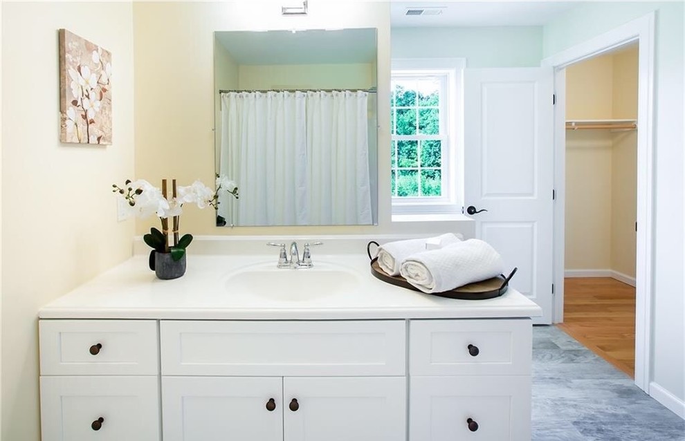 Design ideas for a large traditional bathroom in Bridgeport with shaker cabinets, white cabinets, yellow walls, marble floors, an undermount sink and grey floor.