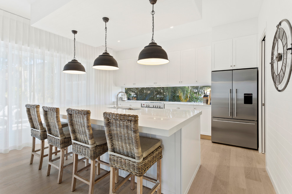 This is an example of a large traditional eat-in kitchen in Gold Coast - Tweed with an undermount sink, raised-panel cabinets, white cabinets, quartz benchtops, window splashback, stainless steel appliances, with island and white benchtop.