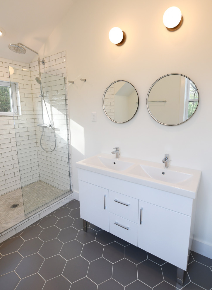 Photo of a mid-sized country master bathroom in New York with flat-panel cabinets, white cabinets, an alcove shower, a one-piece toilet, white tile, ceramic tile, white walls, porcelain floors, an integrated sink, solid surface benchtops, grey floor, white benchtops, a double vanity, a freestanding vanity and vaulted.