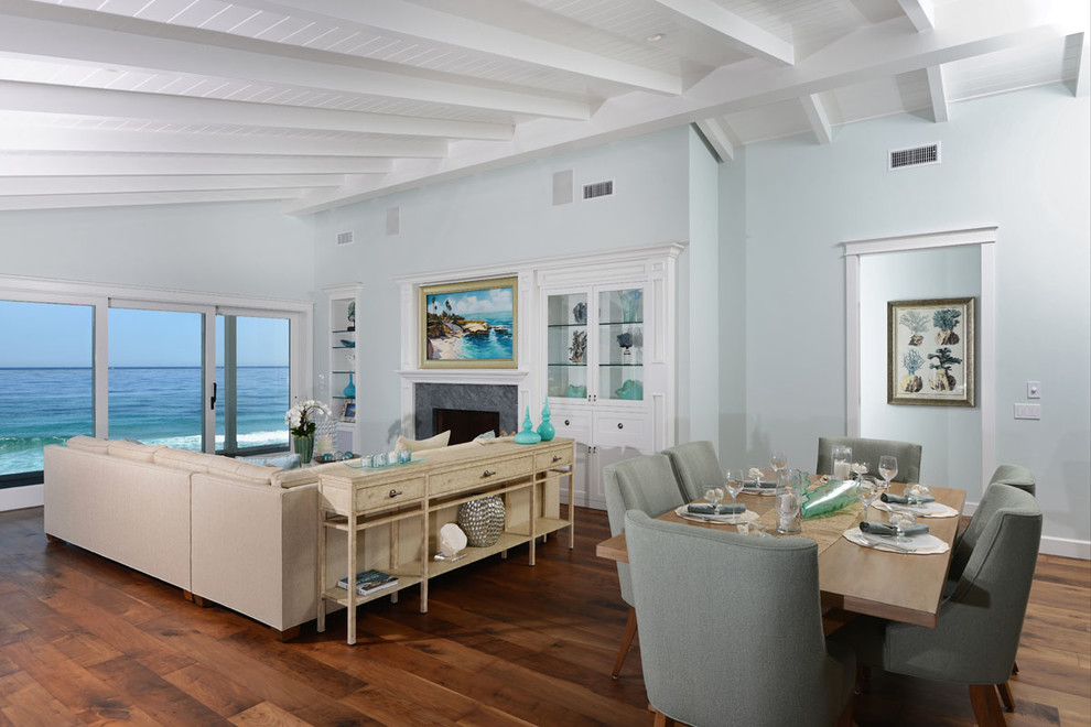 This is an example of a beach style formal open concept living room in San Diego with blue walls, medium hardwood floors, a standard fireplace and no tv.