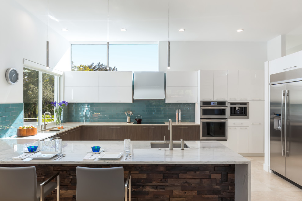 Photo of a mid-sized contemporary u-shaped kitchen in Tampa with a farmhouse sink, flat-panel cabinets, marble benchtops, ceramic splashback, stainless steel appliances, travertine floors, with island, beige floor, white cabinets and blue splashback.