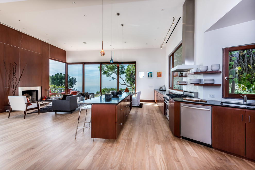 This is an example of a contemporary open plan kitchen in Los Angeles with an undermount sink, flat-panel cabinets, dark wood cabinets, stainless steel appliances, medium hardwood floors and with island.