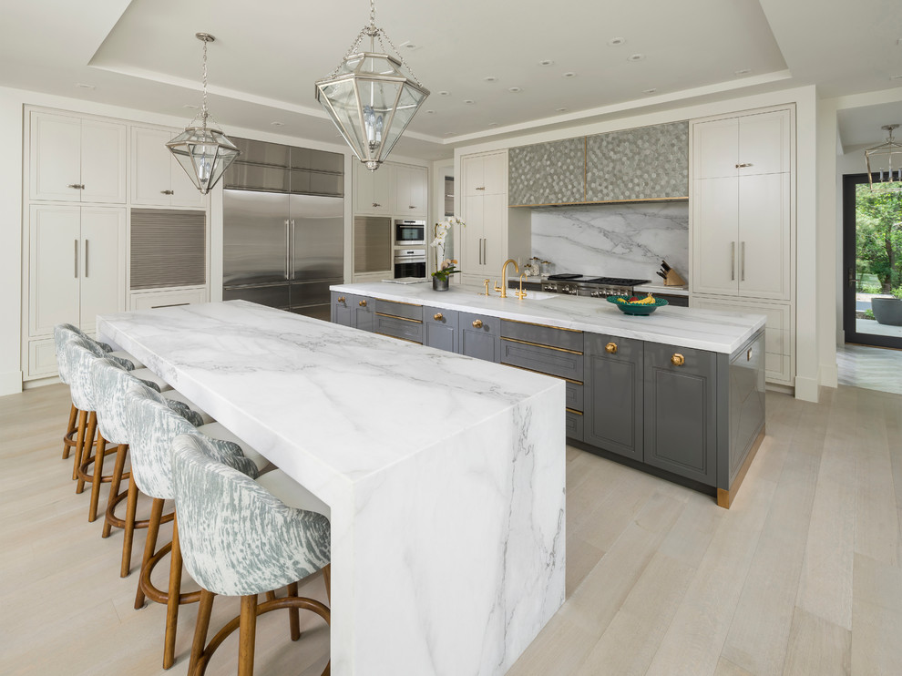 Inspiration for a large contemporary l-shaped open plan kitchen in Salt Lake City with an undermount sink, recessed-panel cabinets, white cabinets, marble benchtops, white splashback, stone slab splashback, stainless steel appliances, light hardwood floors, multiple islands and beige floor.