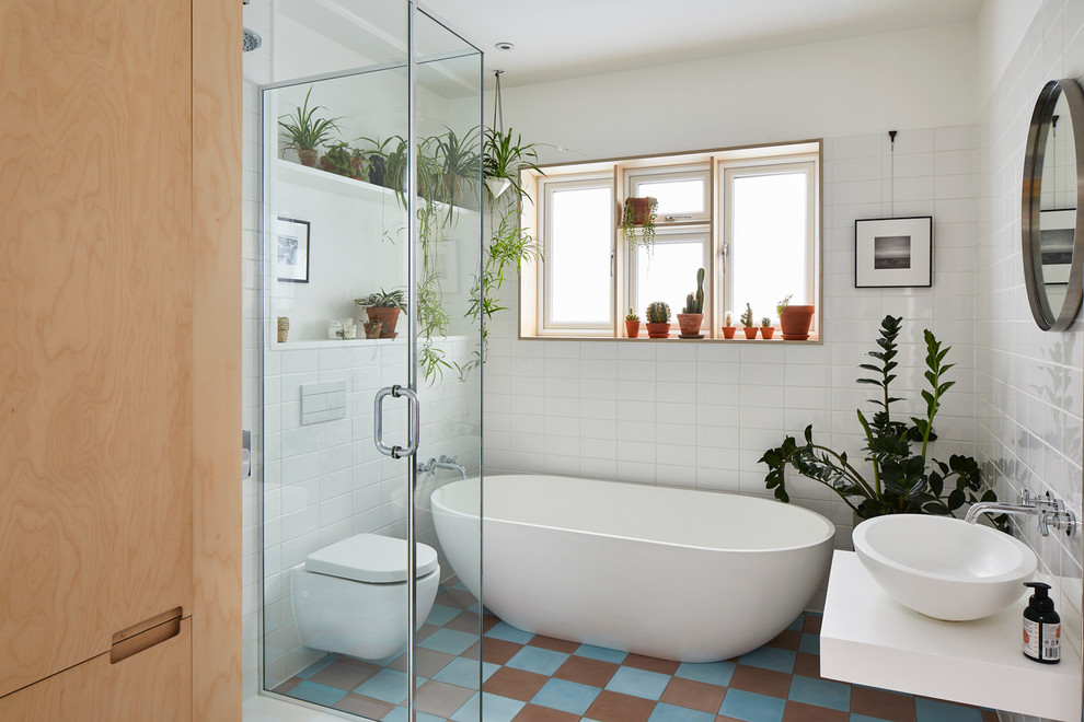 Photo of a midcentury master bathroom in London with a freestanding tub, white tile, white walls, a vessel sink, multi-coloured floor and white benchtops.