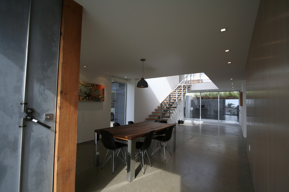 This is an example of a modern separate dining room in San Diego with white walls, concrete floors and no fireplace.