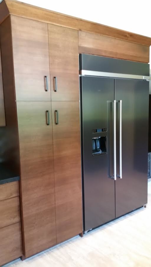 Example of a mid-sized transitional light wood floor and beige floor open concept kitchen design in Houston with flat-panel cabinets, medium tone wood cabinets, solid surface countertops, stainless steel appliances, no island, multicolored backsplash and glass tile backsplash