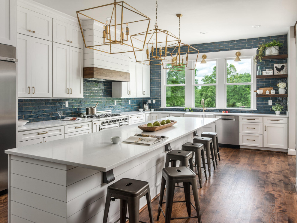 Inspiration for a large country l-shaped brown floor kitchen remodel in Nashville with a farmhouse sink, shaker cabinets, white cabinets, blue backsplash, ceramic backsplash, stainless steel appliances, an island and gray countertops