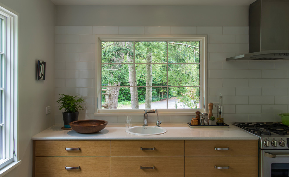 Inspiration for a mid-sized transitional galley medium tone wood floor enclosed kitchen remodel in DC Metro with a drop-in sink, flat-panel cabinets, light wood cabinets, quartz countertops, white backsplash, ceramic backsplash, stainless steel appliances and no island