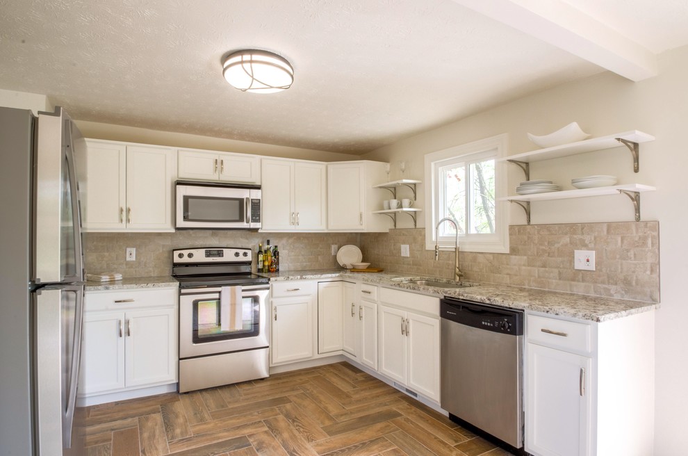 Kitchen - mid-sized transitional u-shaped porcelain tile and brown floor kitchen idea in Cincinnati with an undermount sink, recessed-panel cabinets, white cabinets, granite countertops, beige backsplash, stone tile backsplash, stainless steel appliances and no island