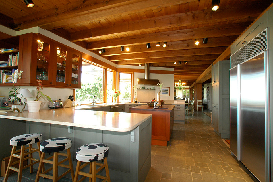 Photo of a mid-sized eclectic u-shaped open plan kitchen in San Francisco with an undermount sink, flat-panel cabinets, medium wood cabinets, limestone benchtops, beige splashback, stone slab splashback, stainless steel appliances, ceramic floors and with island.