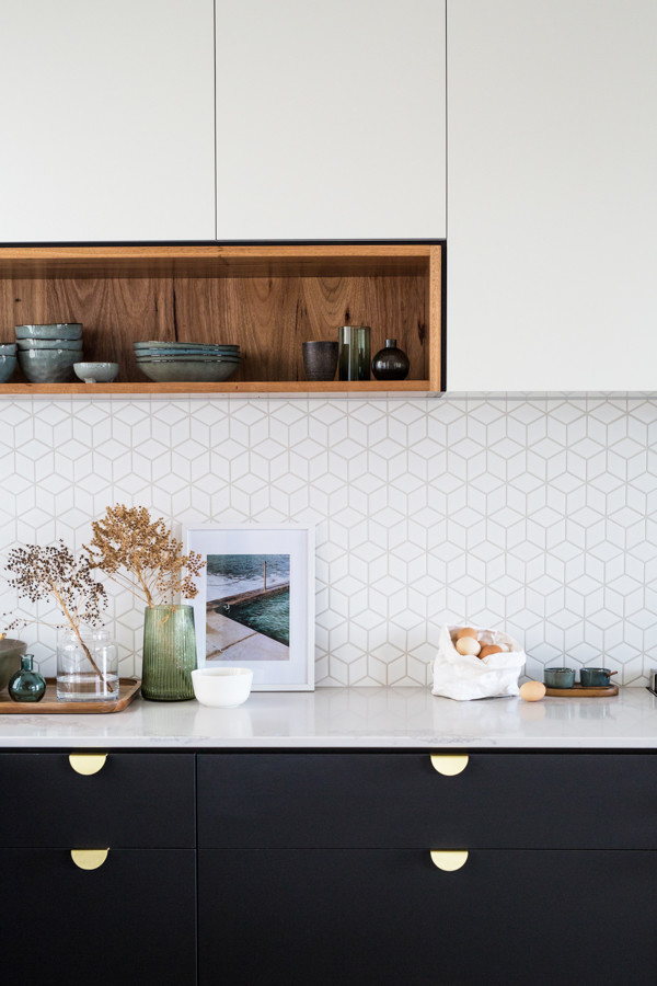 Inspiration for a large industrial l-shaped kitchen pantry in Other with a single-bowl sink, flat-panel cabinets, black cabinets, solid surface benchtops, white splashback, ceramic splashback, black appliances, concrete floors, with island, grey floor and white benchtop.