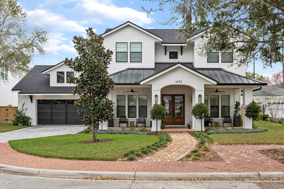 Photo of a transitional two-storey white house exterior in Orlando with a gable roof and a mixed roof.