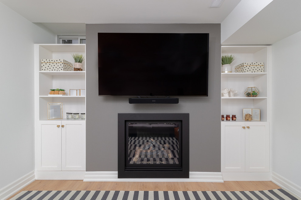 Inspiration for a mid-sized transitional look-out basement in Toronto with grey walls, laminate floors, a standard fireplace and brown floor.