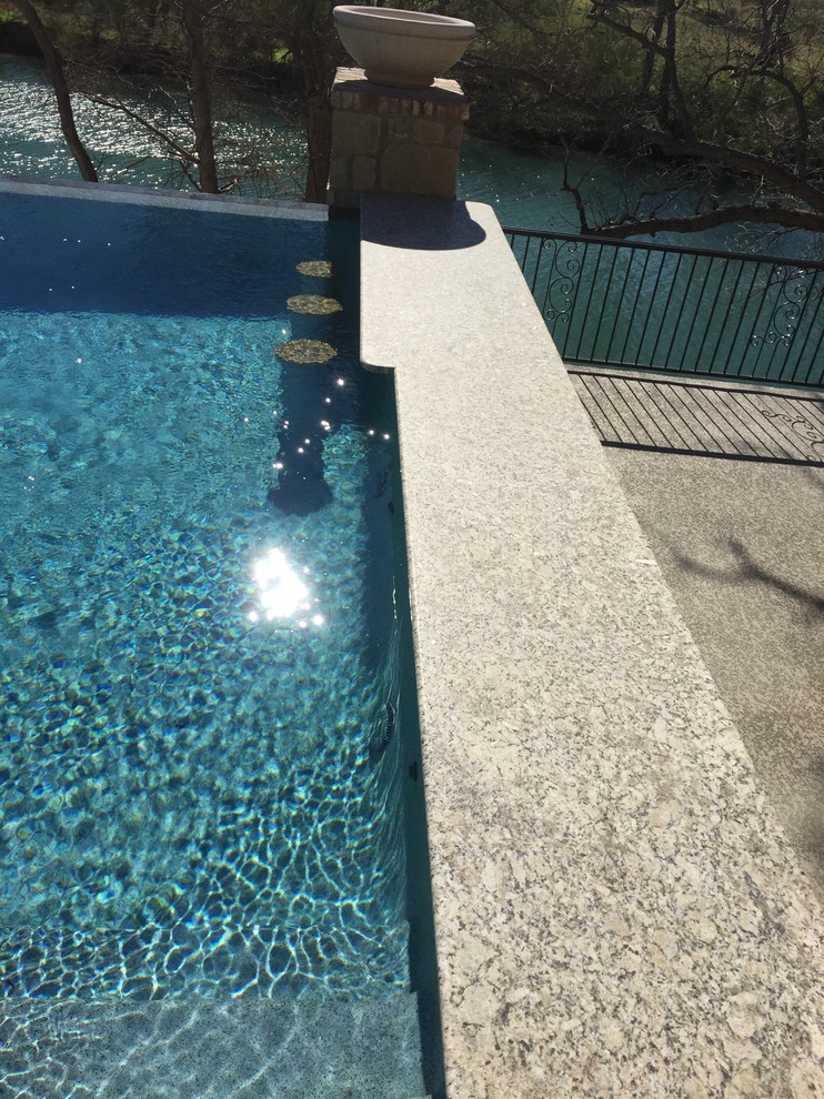 Example of a mid-sized backyard stamped concrete and custom-shaped infinity hot tub design in Austin
