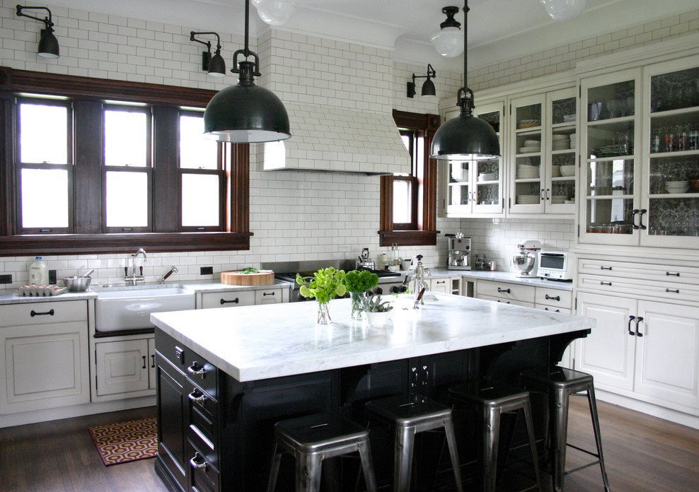 Example of a large transitional l-shaped dark wood floor and brown floor eat-in kitchen design with a farmhouse sink, raised-panel cabinets, white cabinets, marble countertops, white backsplash, subway tile backsplash, stainless steel appliances and an island