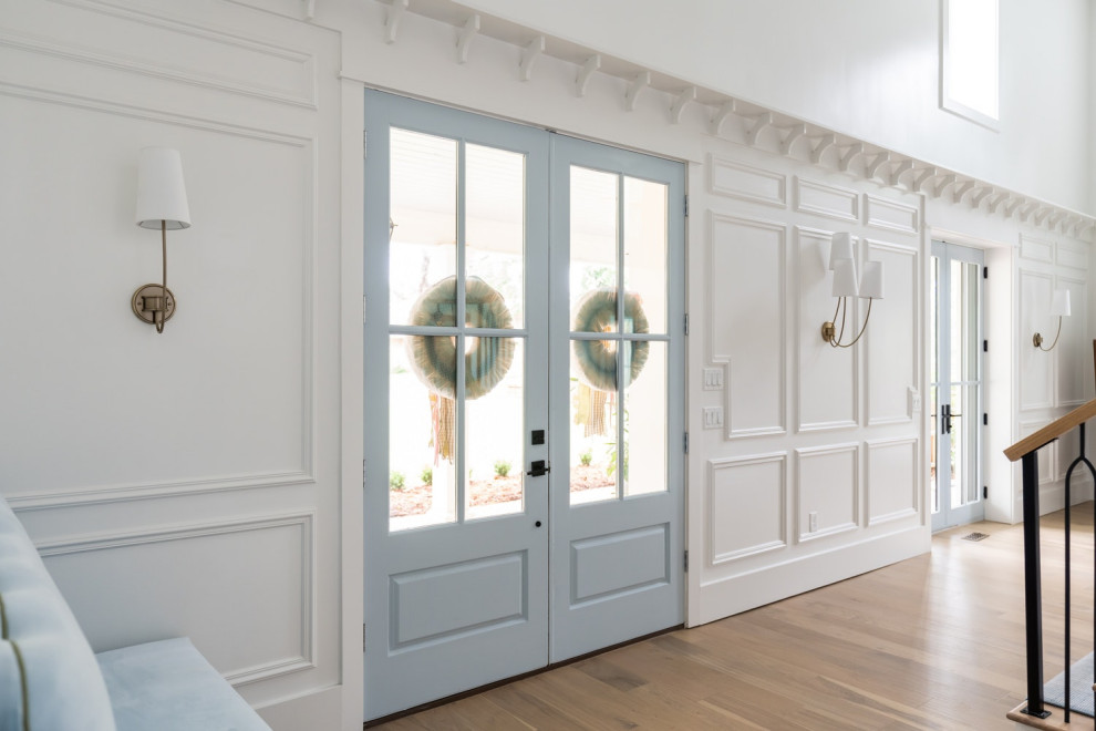 На фото: большое фойе в классическом стиле с белыми стенами, светлым паркетным полом, двустворчатой входной дверью, синей входной дверью, кессонным потолком и панелями на части стены