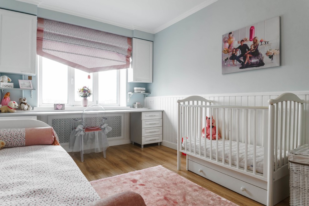 Photo of a transitional nursery for girls in Other with grey walls, medium hardwood floors and brown floor.