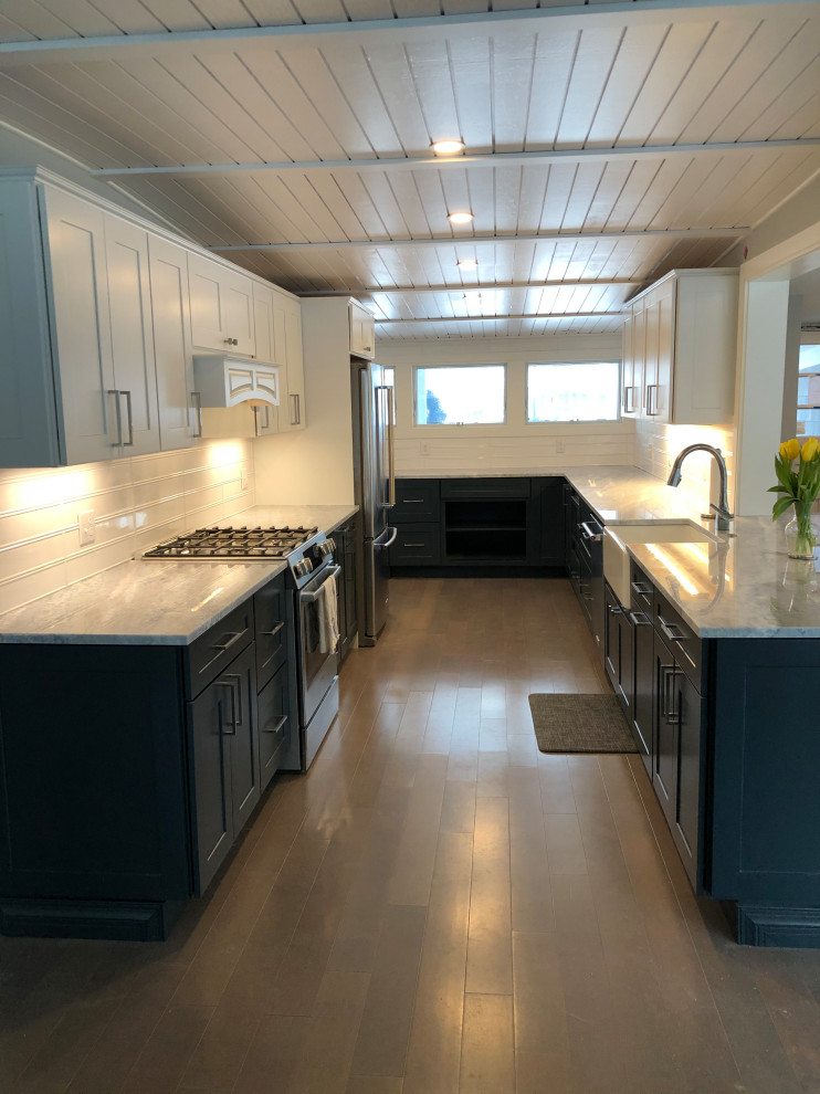 Photo of a large midcentury l-shaped kitchen/diner in New York with a belfast sink, shaker cabinets, blue cabinets, granite worktops, white splashback, metro tiled splashback, stainless steel appliances, light hardwood flooring, no island, grey floors, grey worktops and a wood ceiling.