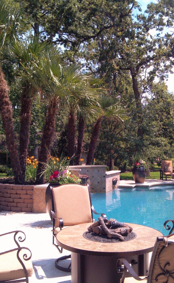 Inspiration for a large tropical backyard custom-shaped natural pool in Houston with a water feature and decking.