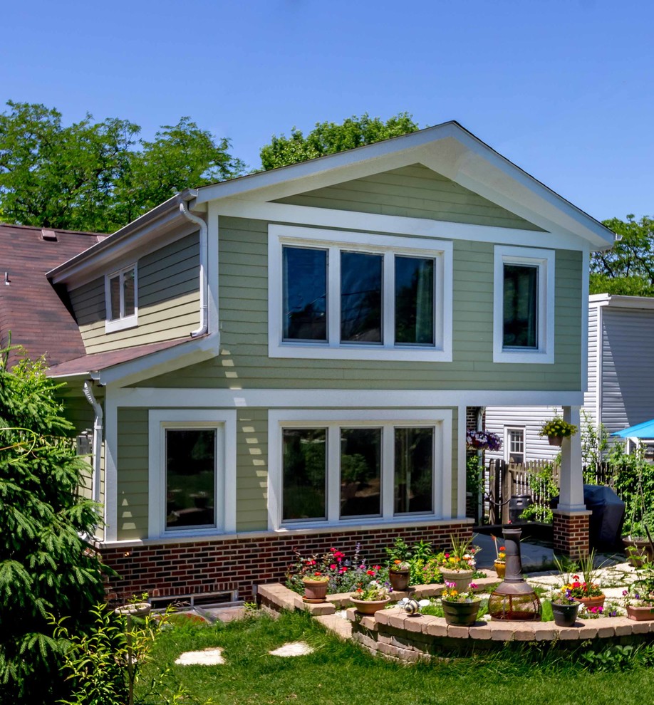 Photo of a large eclectic split-level brick green house exterior in Chicago with a gable roof, a shingle roof, a brown roof and clapboard siding.