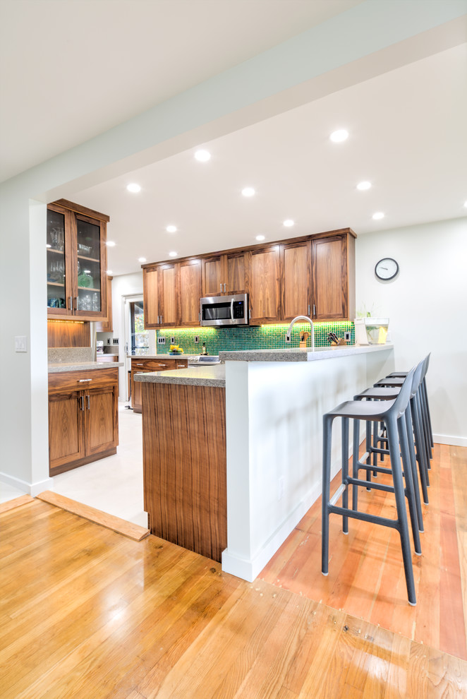 Mid-sized transitional l-shaped eat-in kitchen in Hawaii with medium wood cabinets, granite benchtops, green splashback, mosaic tile splashback, stainless steel appliances, porcelain floors, no island, an undermount sink and shaker cabinets.