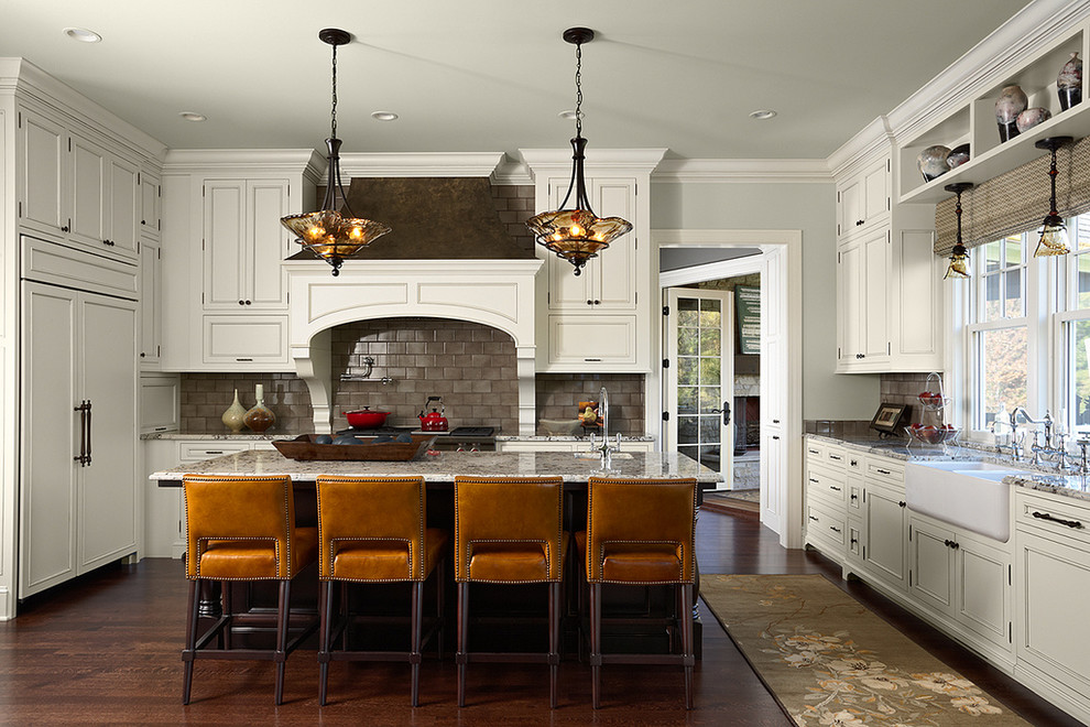 This is an example of a traditional u-shaped separate kitchen in Minneapolis with a farmhouse sink, recessed-panel cabinets, beige cabinets, grey splashback, panelled appliances, dark hardwood floors and with island.