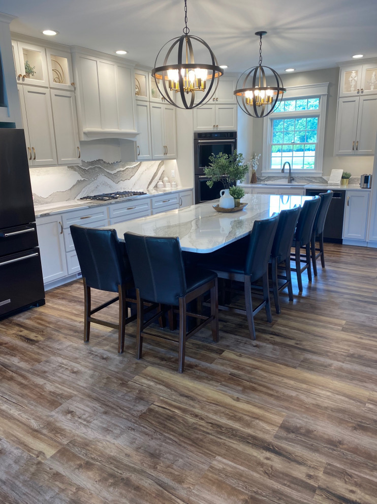Large transitional l-shaped medium tone wood floor and brown floor open concept kitchen photo with an undermount sink, flat-panel cabinets, white cabinets, quartz countertops, multicolored backsplash, quartz backsplash, black appliances, an island and multicolored countertops